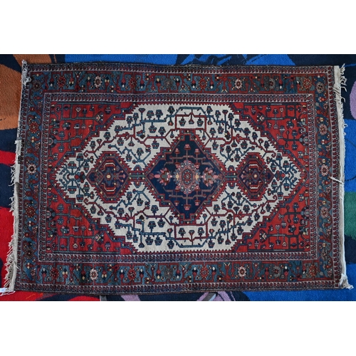 138 - An early 20th century Persian Bakhari rug, the navy triple medallion on cream gorund with red corner... 