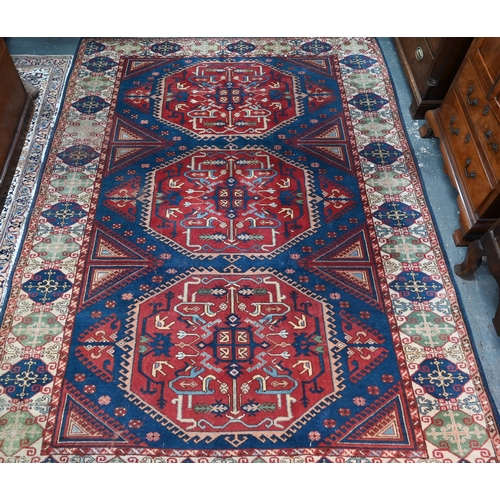 143 - An old Turkish Caucasian design carpet  blue ground with three red ground lozenges with conform... 