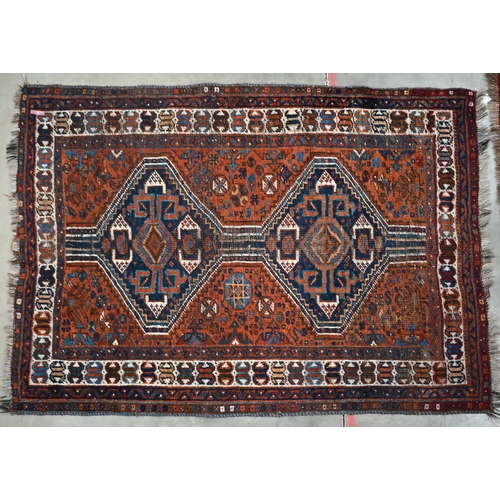 104 - Persian Shiraz red ground rug with double pole-linked navy lozenge medallion, 150 x 105 cm