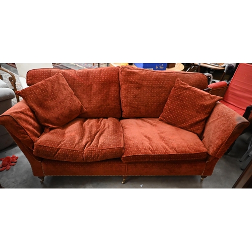 115 - A Duresta three seater sofa with patterned red fabric and three turned front supports with brass cas... 