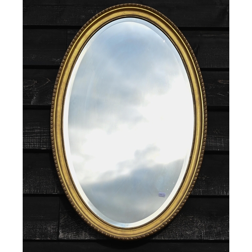 126 - An Edwardian bevelled oval wall mirror in decorative moulded gilt frame, 84 x 54 cm