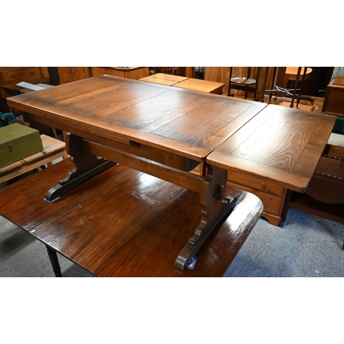 183 - An Ercol elm draw leaf dining table, on shaped trestle ends united by a mid-height centre stretcher,... 