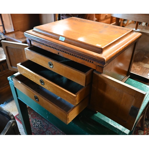 224 - An oak canteen cabinet, the hinged top over a pair of cabinet doors enclosing three graduated drawer... 