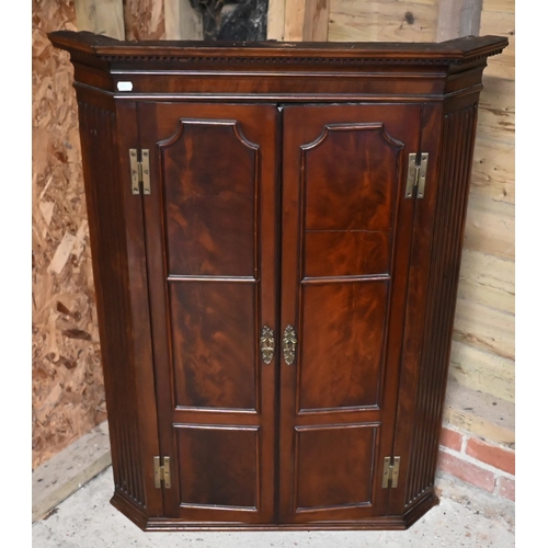 228 - A Georgian mahogany corner hanging cupboard, the dentil moulded cornice over panelled doors