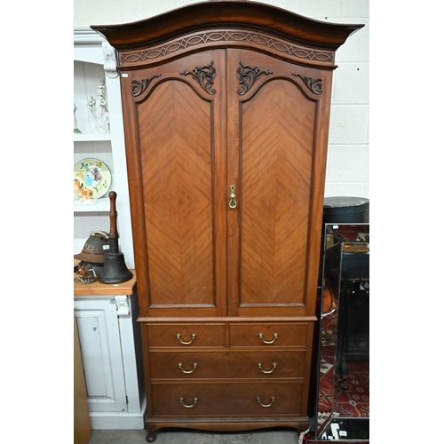 50 - A mahogany arch-top combination wardrobe, the panelled doors enclosing pull-out hangers on chest bas... 