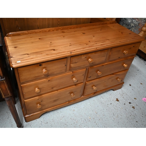 546 - A modern stained pine seven drawer chest with turned handles, 134 cm wide x 45 cm deep x 78 cm high