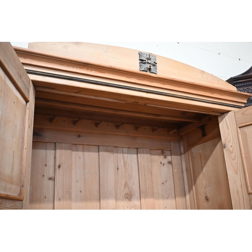 57 - An antique pine knock-down wardrobe with twin panelled doors enclosing open hanging space on single ... 