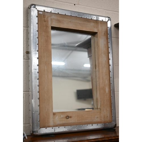 84 - An industrial design wall mirror in hardwood and studded sheet-metal frame, 72 cm wide x 90 cm high