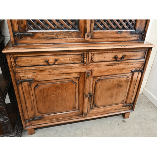 134 - An Indian hardwood two part cabinet with open lattice panelled doors on base with two drawers and pa... 