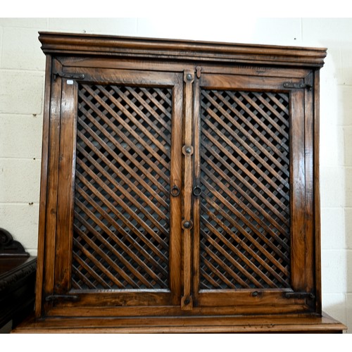 134 - An Indian hardwood two part cabinet with open lattice panelled doors on base with two drawers and pa... 