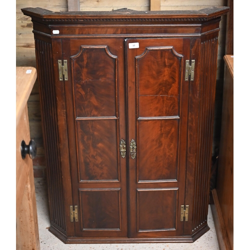 10 - A Georgian mahogany corner hanging cupboard, the dentil moulded cornice over a pair of framed and pa... 