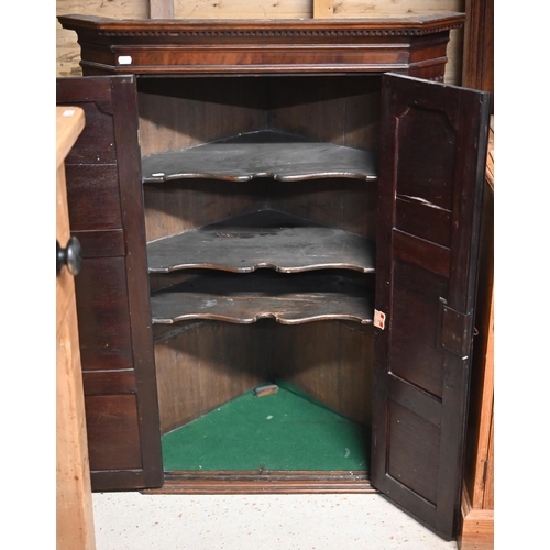 10 - A Georgian mahogany corner hanging cupboard, the dentil moulded cornice over a pair of framed and pa... 