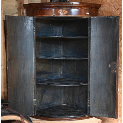 102 - A Georgian inlaid mahogany bowfront corner cupboard, brass fittings