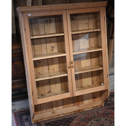 106 - A stripped pine twin glazed door hanging cabinet, 105 cm x 24 cm x 142 cm h o/all