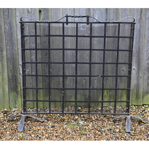 123 - #A large wrought iron and wire-mesh panelled spark guard, 140 cm w x 110 cm h o/a including base/fee... 