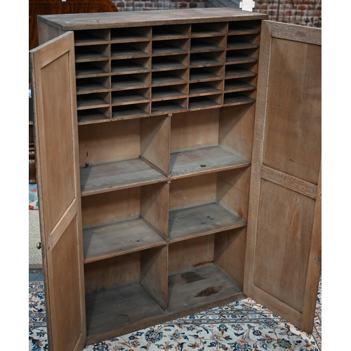 15 - A two door oak cupboard, the interior fitted with pigeon holes and shelves, 115 cm x 40 cm x 178 cm ... 