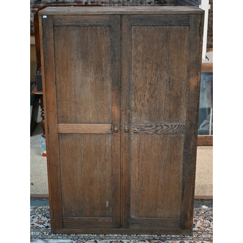 15 - A two door oak cupboard, the interior fitted with pigeon holes and shelves, 115 cm x 40 cm x 178 cm ... 
