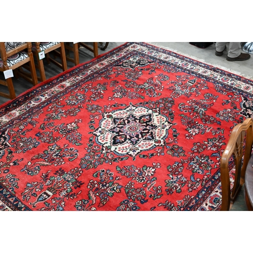 An Indo-Persian Sarouk carpet, the traditional floral design on red ground with ivory palmette border, 250 x 308 cm