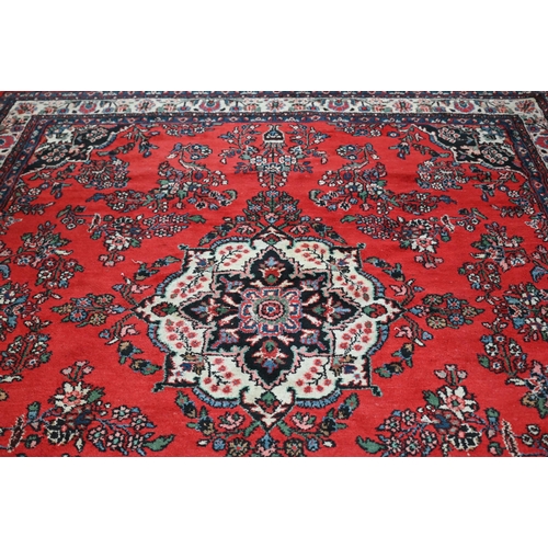 188 - An Indo-Persian Sarouk carpet, the traditional floral design on red ground with ivory palmette borde... 