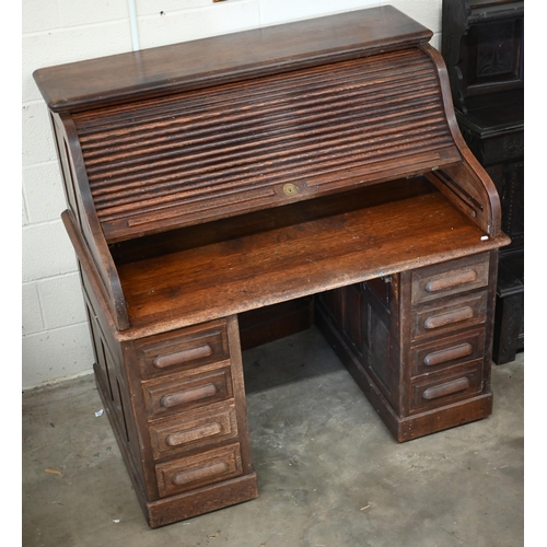 204 - An early 20th century oak roll-top desk with sliding tambour panel enclosing fitted interior over ei... 