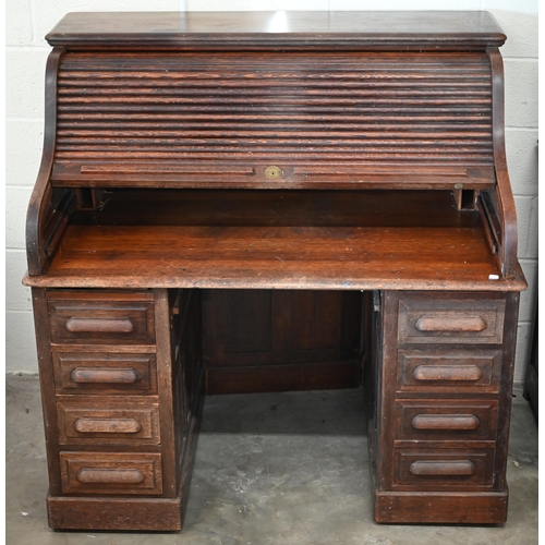 204 - An early 20th century oak roll-top desk with sliding tambour panel enclosing fitted interior over ei... 