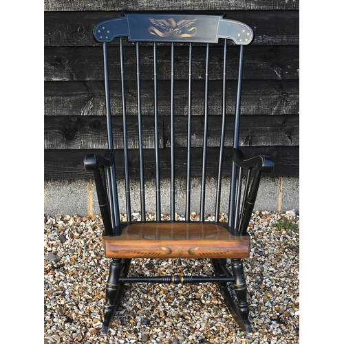 225 - An ebonised spindle back rocking chair with stencilled gilt eagle to crest rail