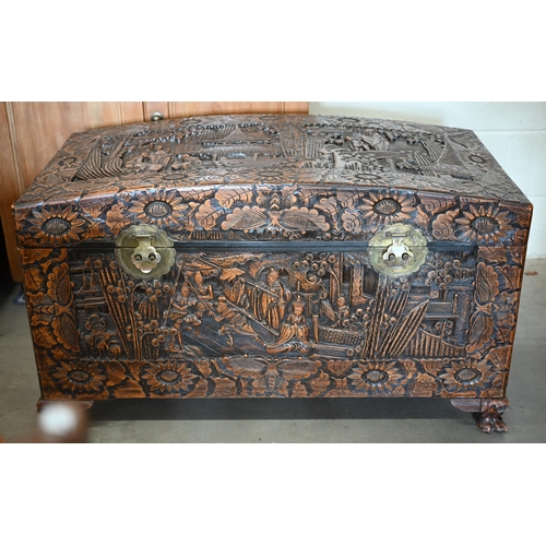 256 - A large Chinese dome-top camphorwood blanket chest extensively carved with landscapes and figures, 1... 