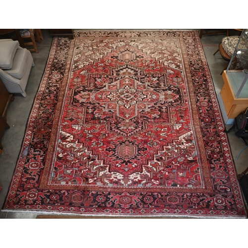 295 - A Persian Heriz carpet, large central medalion on red ground, dark brown rosette border, 387 cm x 31... 