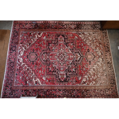 295 - A Persian Heriz carpet, large central medalion on red ground, dark brown rosette border, 387 cm x 31... 