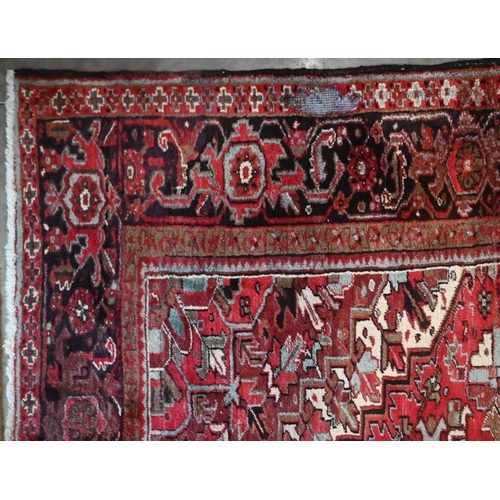 295 - A Persian Heriz carpet, large central medalion on red ground, dark brown rosette border, 387 cm x 31... 