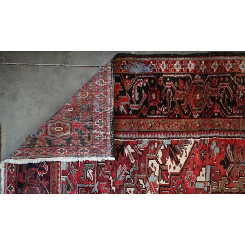 295 - A Persian Heriz carpet, large central medalion on red ground, dark brown rosette border, 387 cm x 31... 