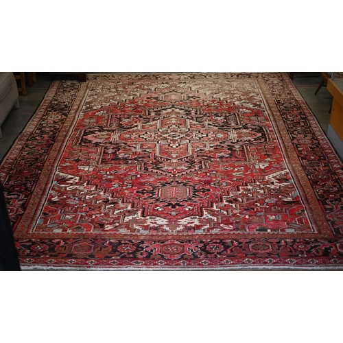 295 - A Persian Heriz carpet, large central medalion on red ground, dark brown rosette border, 387 cm x 31... 