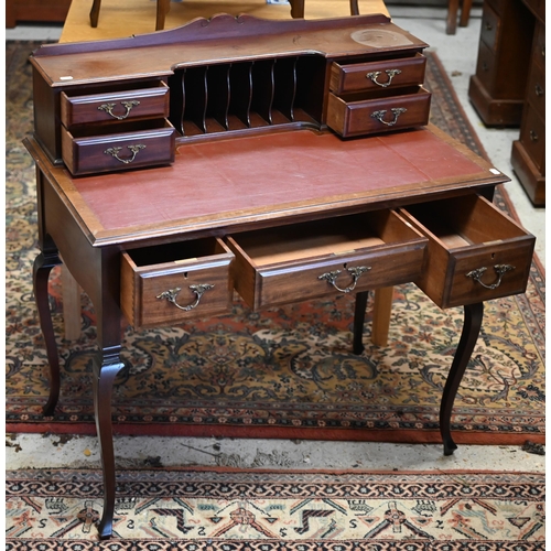 73 - An Edwardian Carlton House style writing table, with burgundy leatherette top, raised on slender cab... 