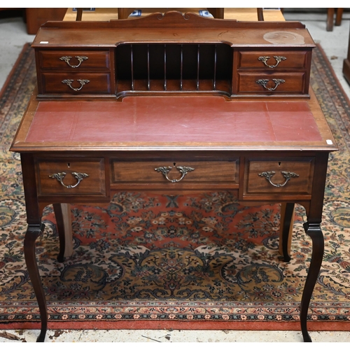 73 - An Edwardian Carlton House style writing table, with burgundy leatherette top, raised on slender cab... 