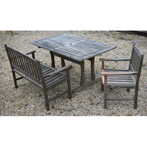 128 - A rectangular weathered teak garden/patio table 150 cm x 90 cm x 72 cm h to/w a two-seater slatted b... 