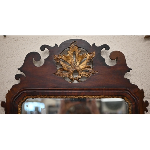 204A - A Georgian wall mirror in fret cut mahogany frame with gilt foliate crest roundel, 93 cm x 50 cm