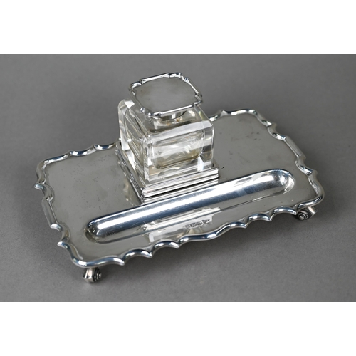 110 - A heavy quality silver inkstand with silver-topped square cut glass inkwell, shaped rim and four scr... 