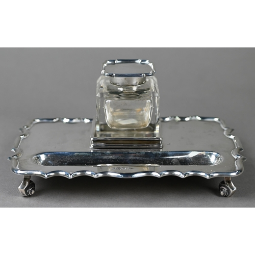 110 - A heavy quality silver inkstand with silver-topped square cut glass inkwell, shaped rim and four scr... 