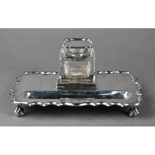 110 - A heavy quality silver inkstand with silver-topped square cut glass inkwell, shaped rim and four scr... 