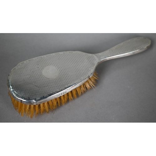 115 - An engine-turned silver hairbrush and mirror set, to/w a similar nail-buffer in glass pot (lacks pad... 