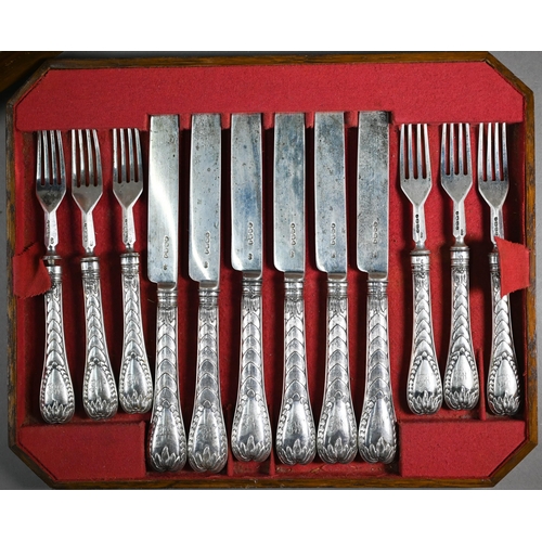 123 - A Victorian walnut-cased set of eighteen dessert knives and forks with silver blades/tines and decor... 