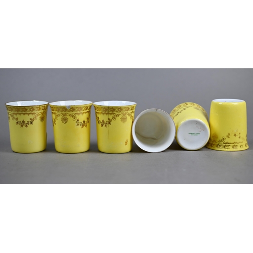 17 - An Edwardian set of six Spode yellow and gilt coffee cans, in pierced silver holders with scroll han... 