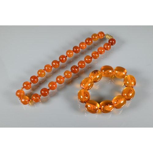 225 - A row of circular amber beads double knotted throughout, approx 40g all in to/w a faux amber bead br... 