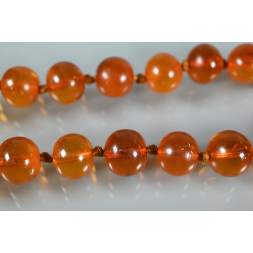 225 - A row of circular amber beads double knotted throughout, approx 40g all in to/w a faux amber bead br... 