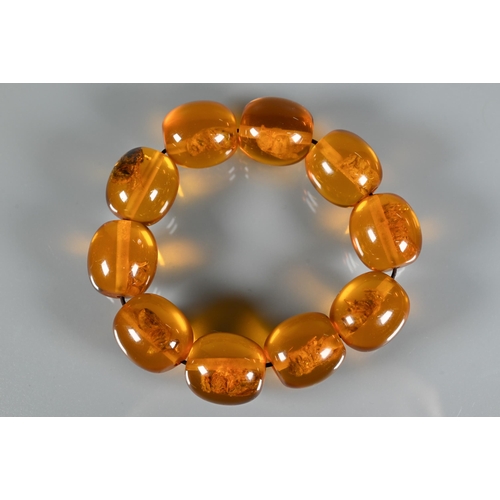 225 - A row of circular amber beads double knotted throughout, approx 40g all in to/w a faux amber bead br... 