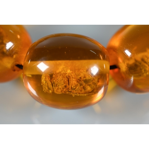 225 - A row of circular amber beads double knotted throughout, approx 40g all in to/w a faux amber bead br... 