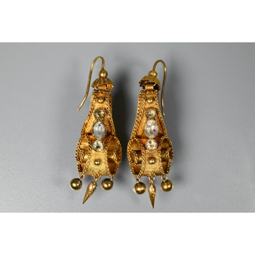 234 - A pair of Victorian textured yellow metal drop earrings of scroll form set with three foil backed st... 