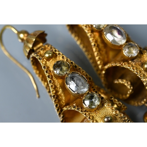 234 - A pair of Victorian textured yellow metal drop earrings of scroll form set with three foil backed st... 