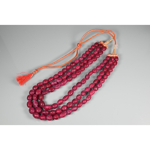 281 - A triple row of graduated carved ruby beads on silk cord, 1 x 0.8 cm the smallest, 1.5 x 1.3 cm the ... 