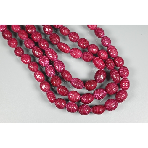 281 - A triple row of graduated carved ruby beads on silk cord, 1 x 0.8 cm the smallest, 1.5 x 1.3 cm the ... 